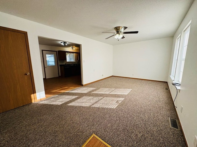 carpeted spare room with ceiling fan and a textured ceiling