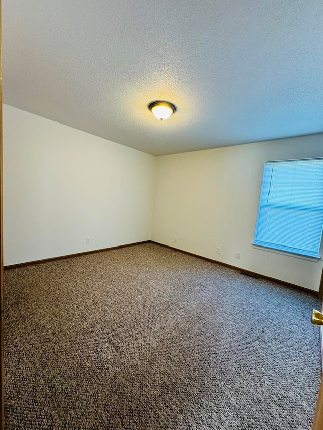 carpeted empty room with a textured ceiling