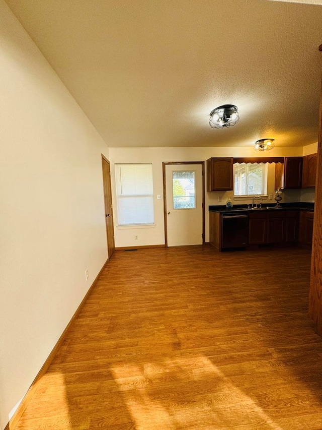 unfurnished living room featuring light hardwood / wood-style flooring, a textured ceiling, and sink