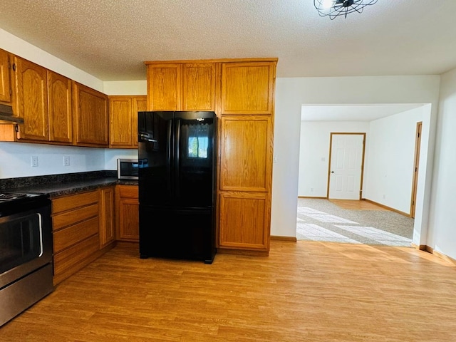 kitchen with extractor fan, a textured ceiling, appliances with stainless steel finishes, and light hardwood / wood-style flooring