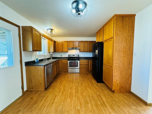 kitchen featuring sink, light wood-type flooring, a textured ceiling, stainless steel appliances, and extractor fan