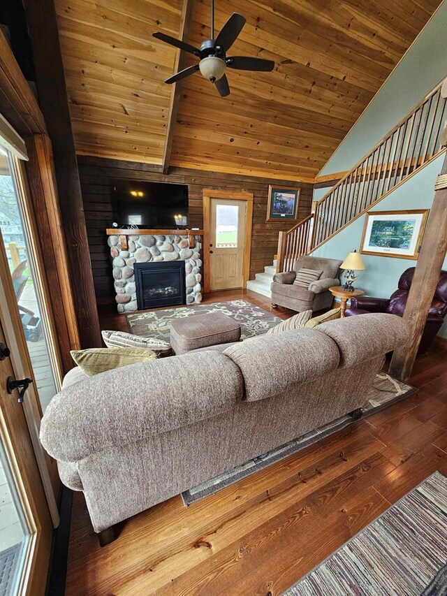 living area featuring stairway, a fireplace, wood ceiling, wooden walls, and hardwood / wood-style floors