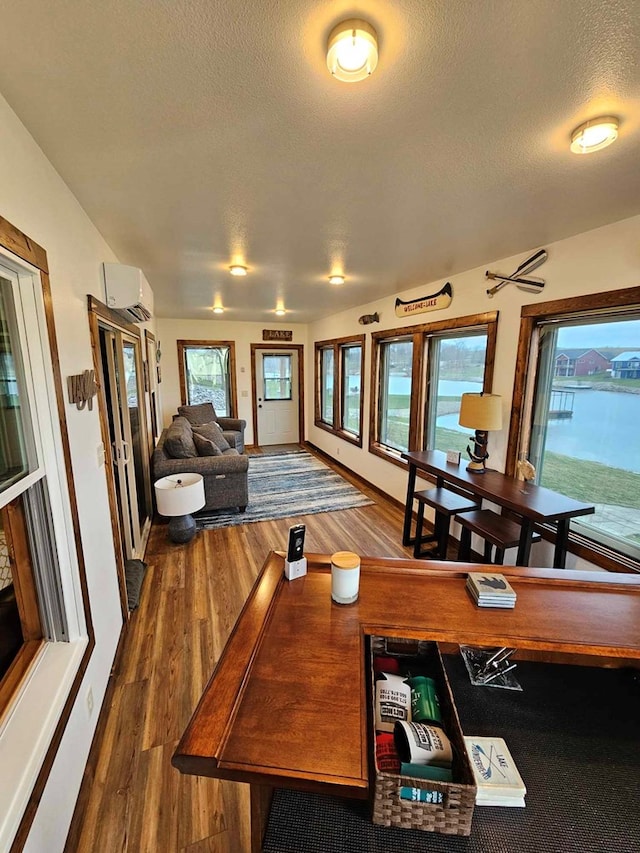 dining room featuring a wall mounted AC, wood finished floors, and a textured ceiling