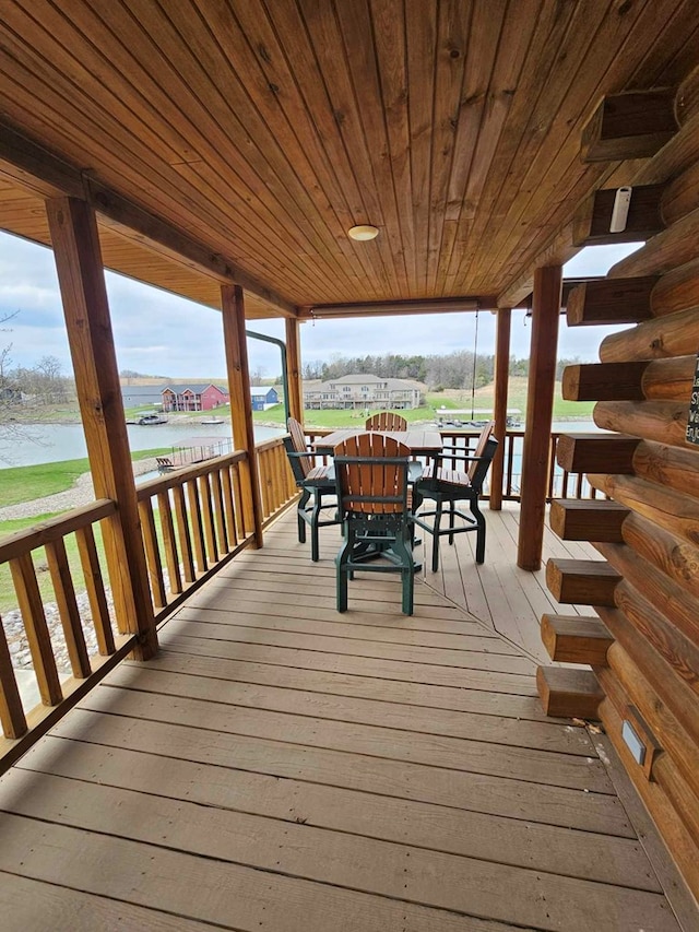 wooden terrace featuring outdoor dining area and a water view