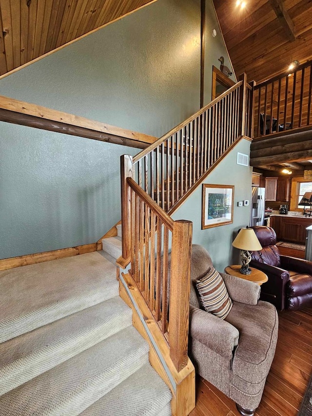 staircase featuring high vaulted ceiling, wooden ceiling, wood-type flooring, baseboards, and visible vents