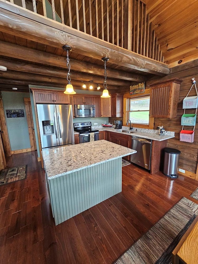 kitchen with a sink, stainless steel appliances, light stone countertops, dark wood-style floors, and a kitchen island