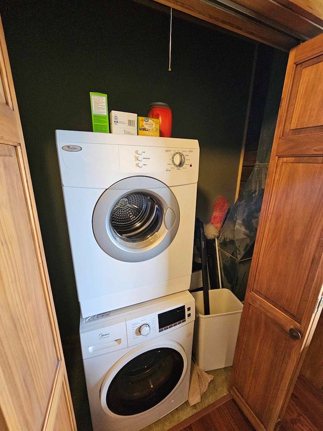 laundry room with wood finished floors, stacked washer and clothes dryer, and laundry area