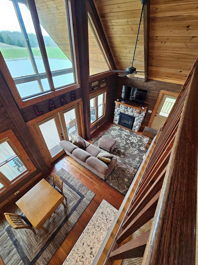 living room with wood walls, a healthy amount of sunlight, a high ceiling, and a fireplace