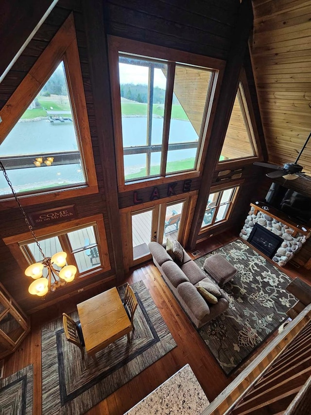 living room with a chandelier, wooden walls, wood finished floors, and a fireplace