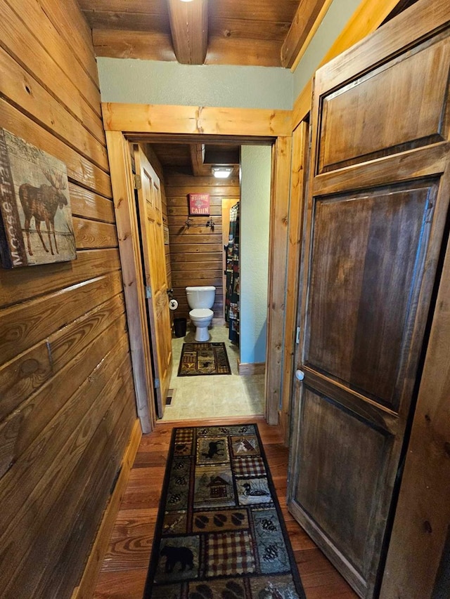 hall featuring wooden ceiling, beam ceiling, wood finished floors, and wooden walls