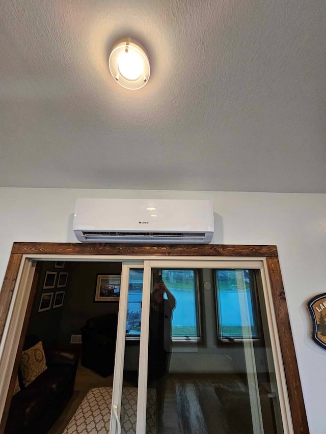 interior space featuring a wall mounted AC and a textured ceiling