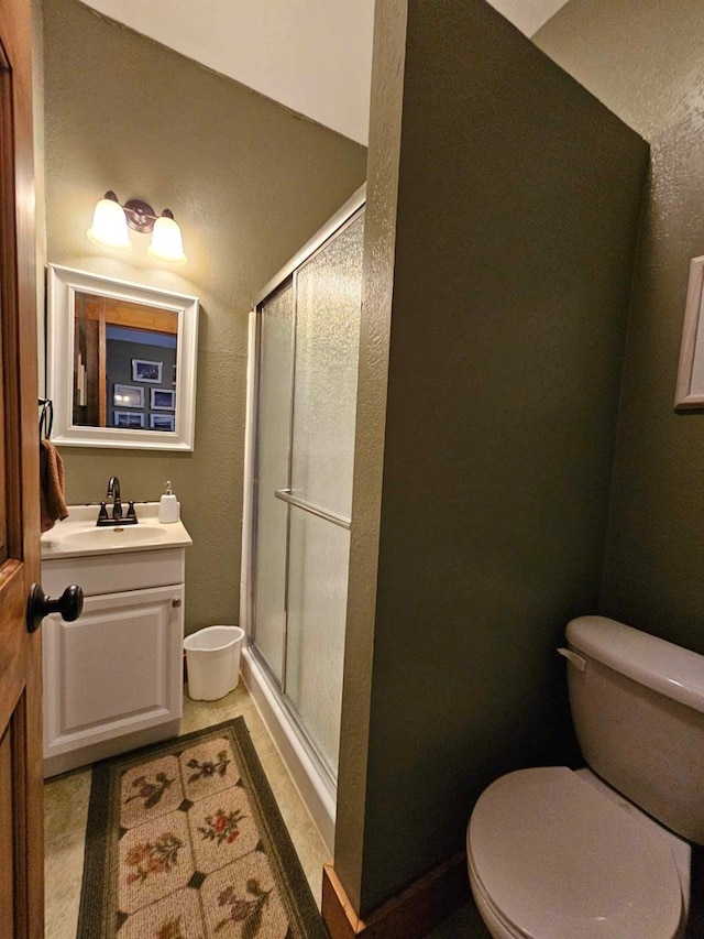 bathroom with a stall shower, vanity, and toilet