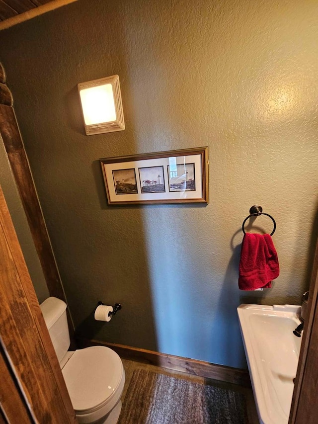 bathroom featuring wood finished floors, toilet, and baseboards