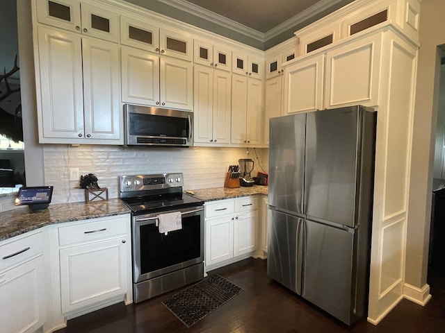 kitchen featuring white cabinetry, stainless steel appliances, tasteful backsplash, crown molding, and dark stone counters