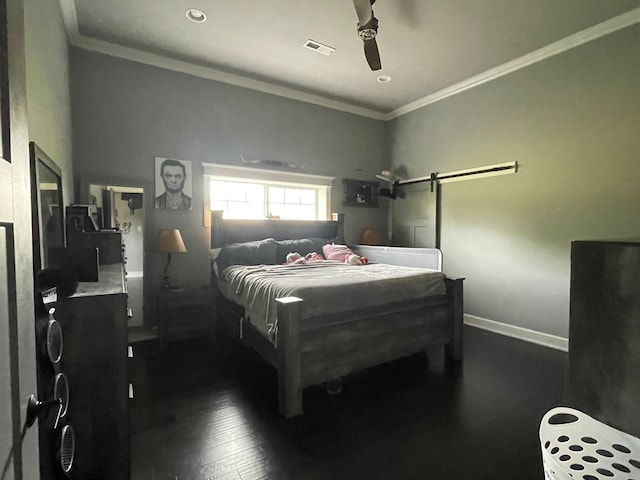 bedroom featuring a barn door, dark hardwood / wood-style floors, ceiling fan, and ornamental molding