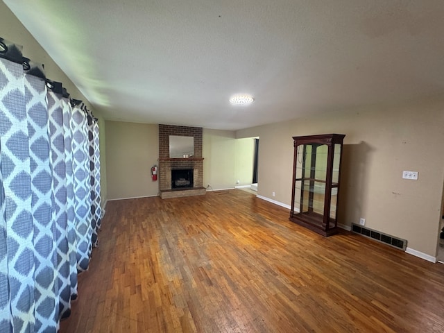2116 S Franklin St, Kirksville, MO 63501 - unfurnished living room featuring wood finished floors, a brick fireplace, and a textured ceiling