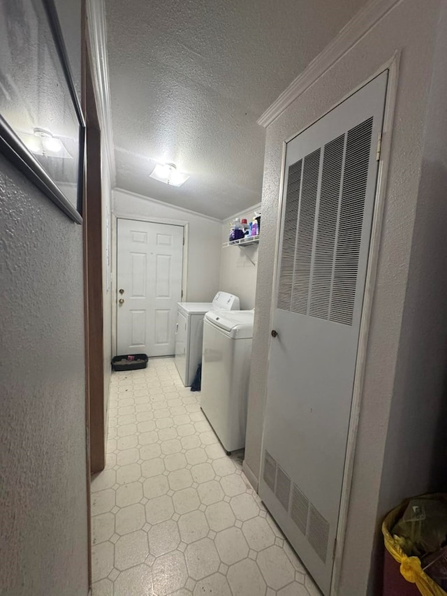 washroom featuring a textured ceiling, washing machine and dryer, and ornamental molding