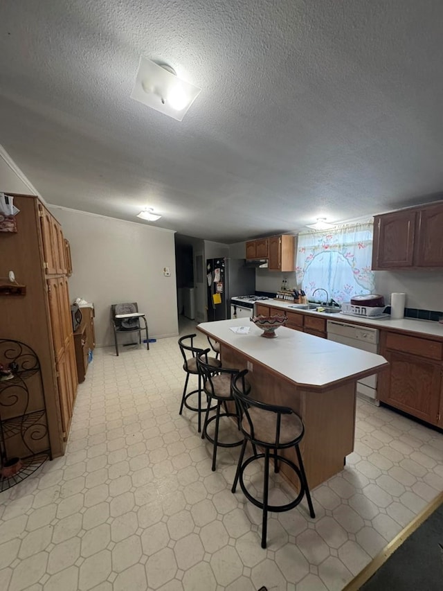 kitchen featuring a center island, white dishwasher, sink, a textured ceiling, and a breakfast bar area