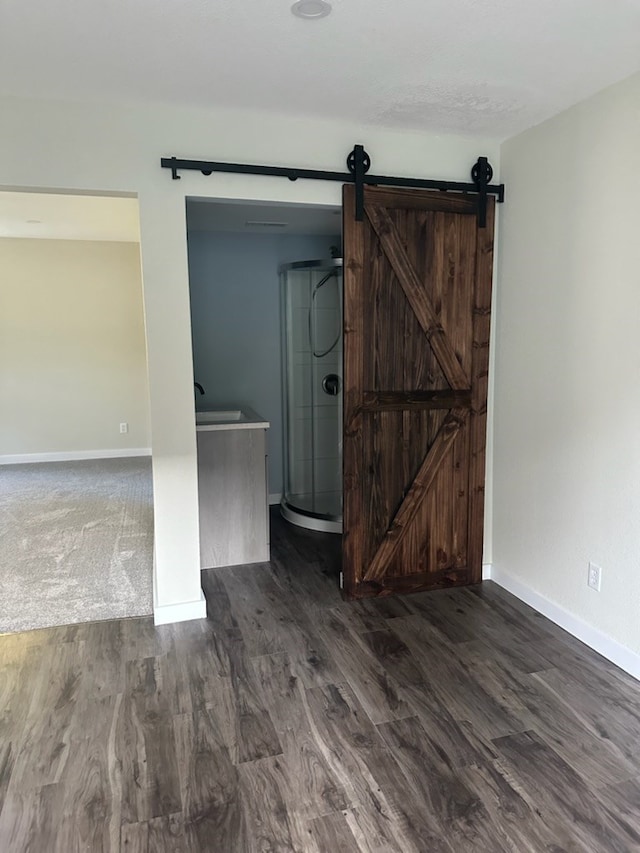 spare room with a barn door and dark hardwood / wood-style floors