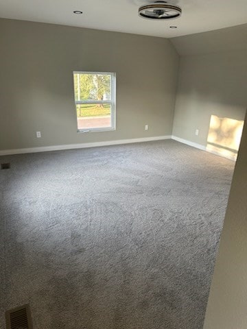 spare room with carpet flooring and vaulted ceiling