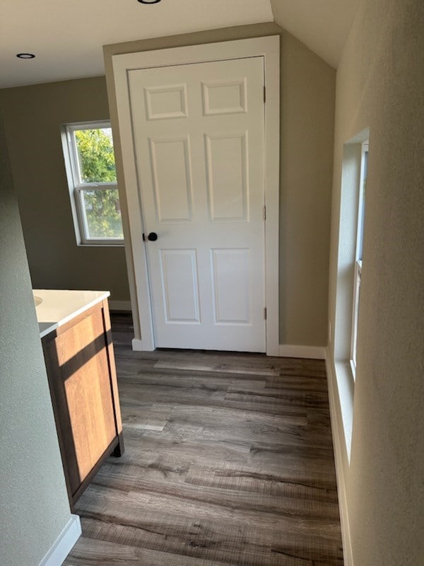 hallway featuring dark wood-type flooring and lofted ceiling