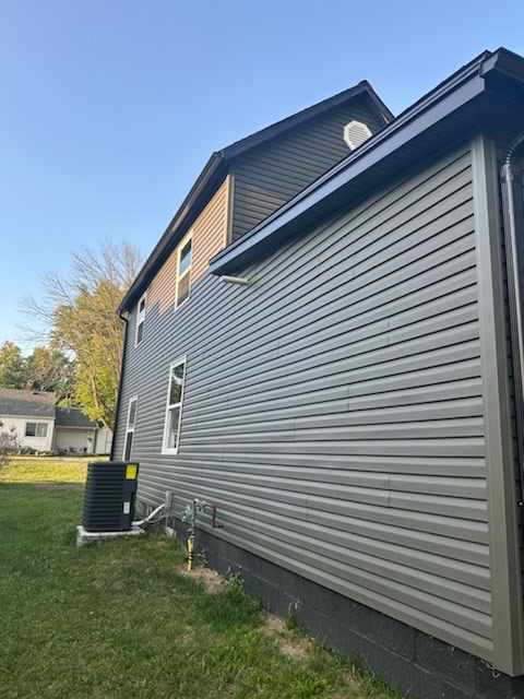 view of property exterior featuring central AC and a lawn