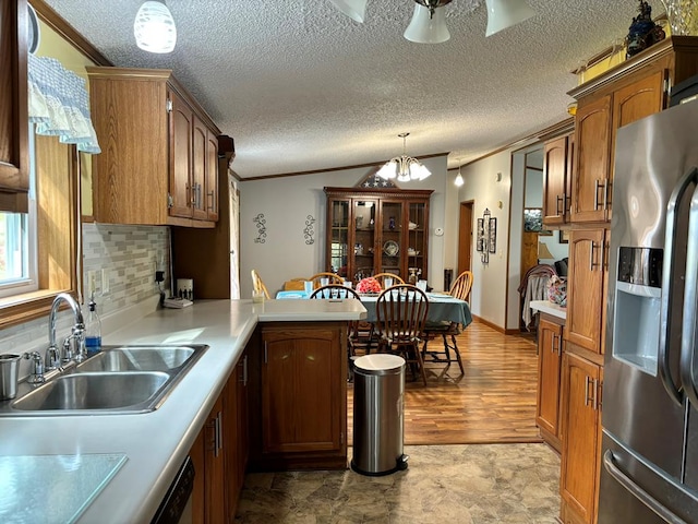 kitchen featuring sink, hanging light fixtures, backsplash, stainless steel fridge, and a chandelier