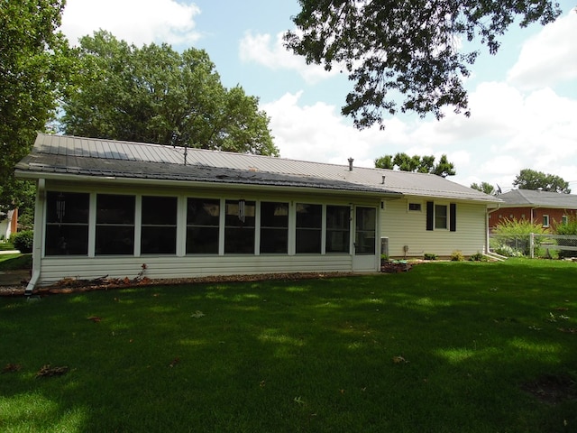 rear view of property with a lawn and a sunroom