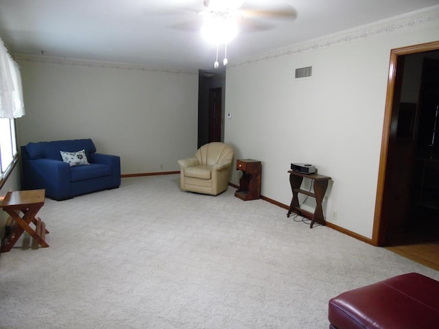 sitting room with carpet flooring, ceiling fan, and ornamental molding