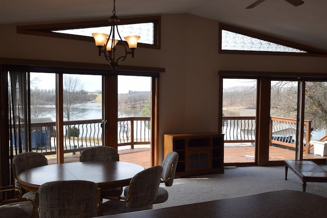 carpeted dining space featuring ceiling fan with notable chandelier, lofted ceiling, and a water view