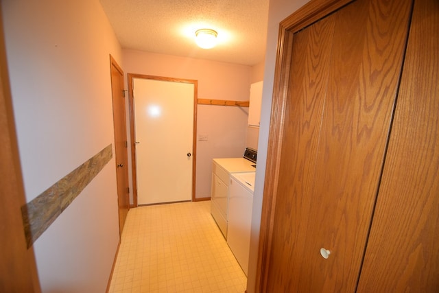 washroom with washing machine and clothes dryer, laundry area, light floors, and a textured ceiling