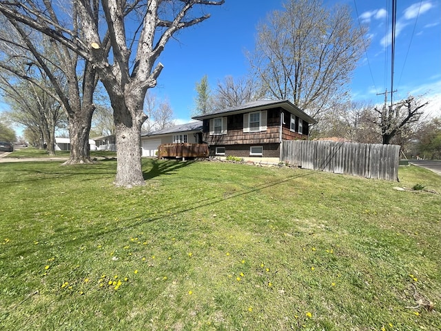 view of yard with a garage, a wooden deck, and fence
