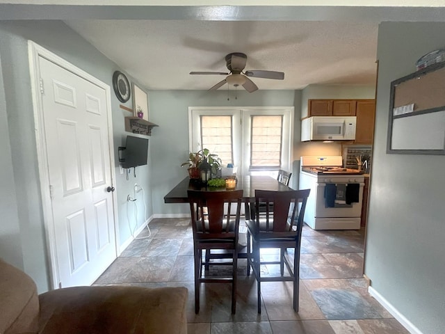 dining space with ceiling fan and baseboards