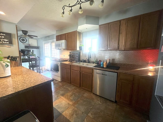 kitchen featuring tasteful backsplash, a sink, ceiling fan, white appliances, and brown cabinetry