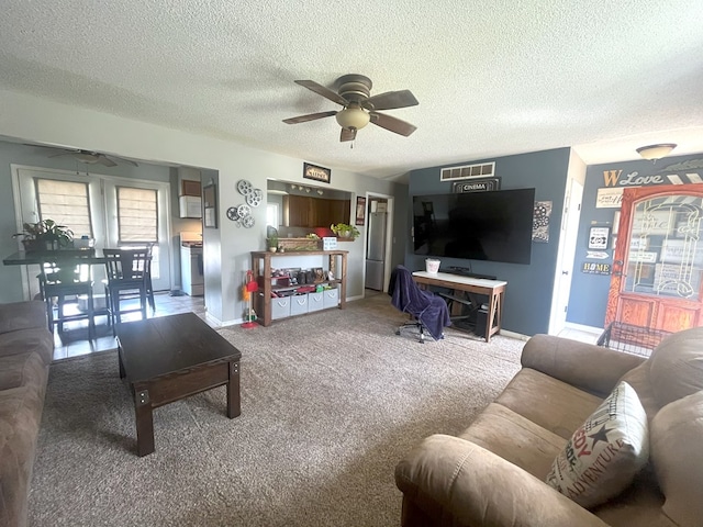 living area with visible vents, baseboards, a ceiling fan, carpet, and a textured ceiling