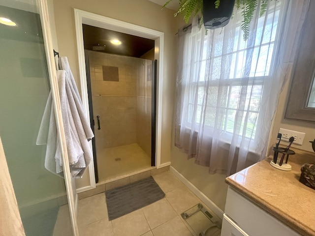 bathroom featuring tile patterned floors, vanity, baseboards, and a stall shower