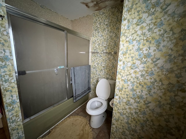 bathroom with enclosed tub / shower combo, toilet, and tile patterned floors