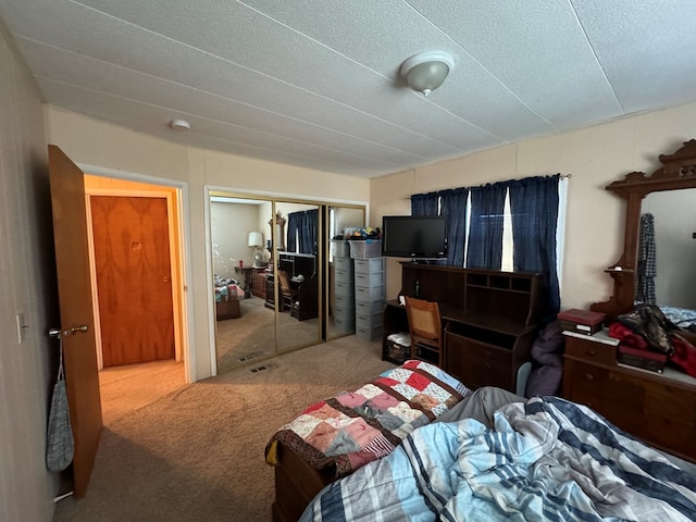 carpeted bedroom with a textured ceiling, visible vents, and a closet