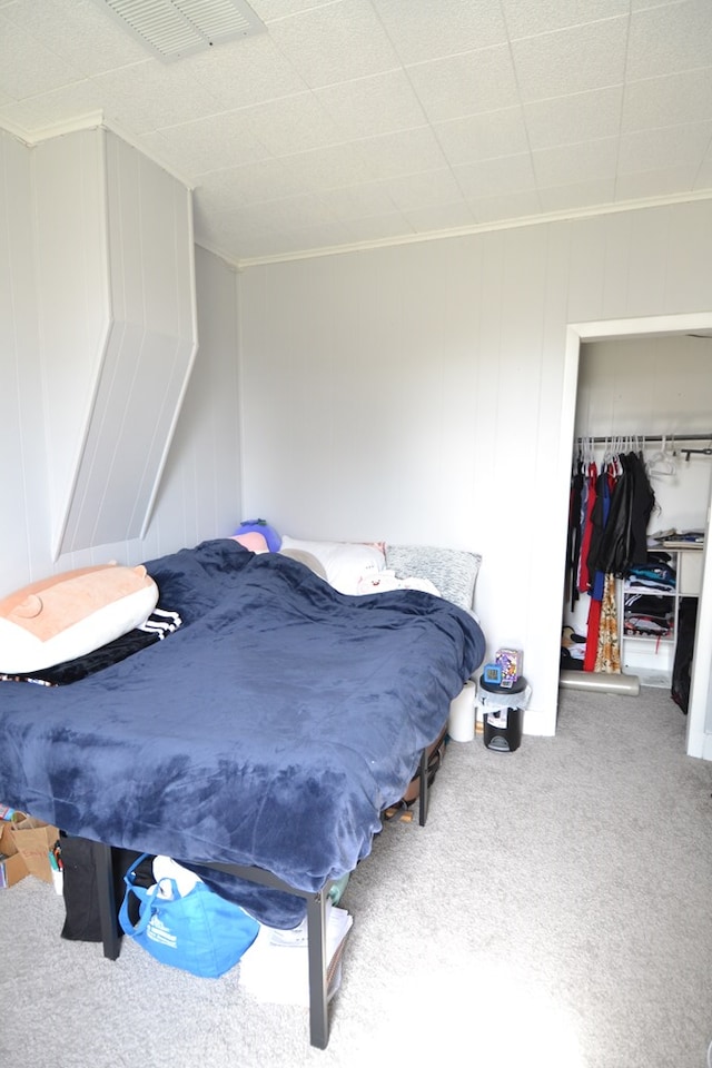 bedroom featuring crown molding, a walk in closet, carpet floors, visible vents, and a closet