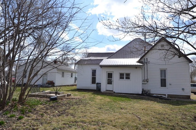 back of property featuring a yard and metal roof