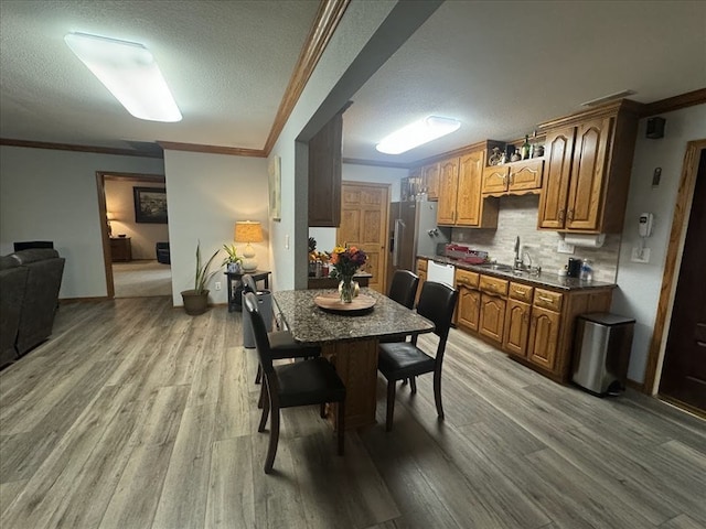 dining room with ornamental molding, light hardwood / wood-style floors, a textured ceiling, and sink