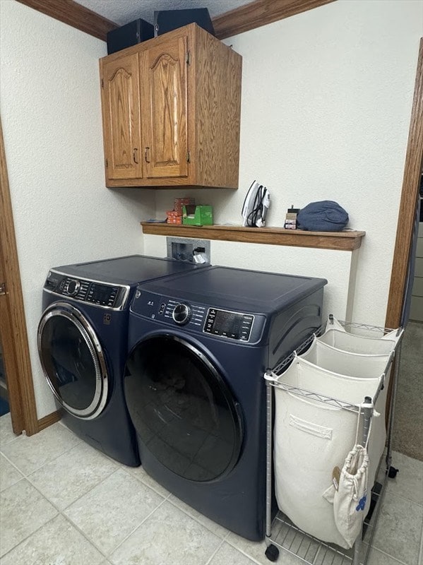 laundry room featuring light tile patterned floors, ornamental molding, separate washer and dryer, and cabinets