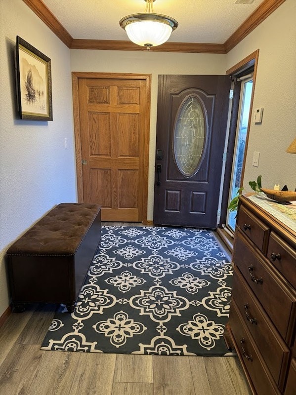 foyer entrance with hardwood / wood-style floors and crown molding