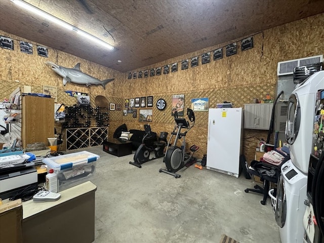 misc room with stacked washer / drying machine, concrete floors, and a workshop area