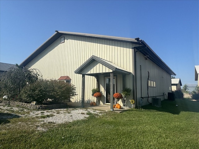 back of property with central AC unit and a lawn