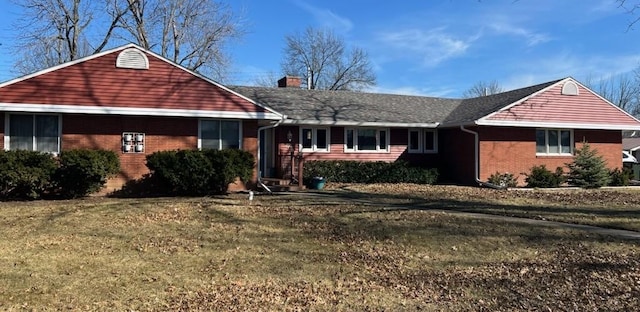 ranch-style home with a front yard, brick siding, and a chimney