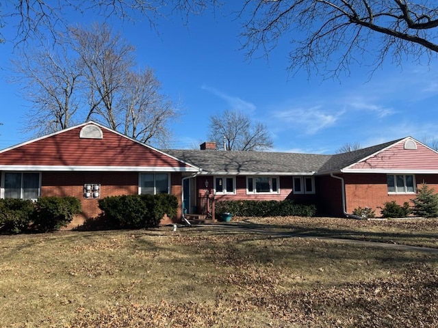 ranch-style home with a front yard, brick siding, and a chimney