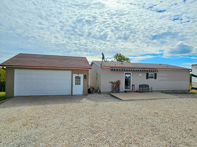 rear view of property with a garage and a patio