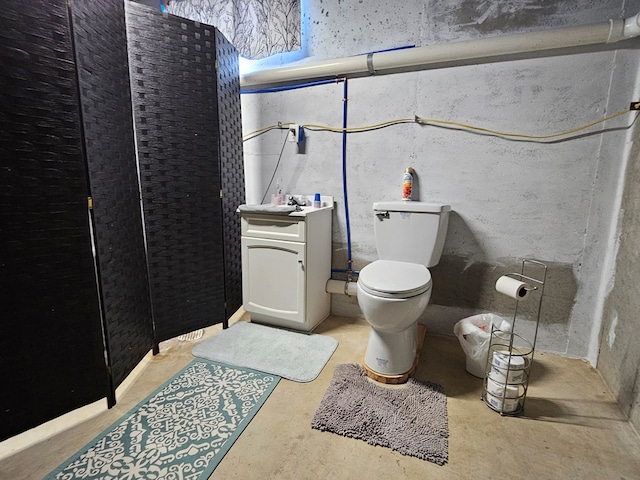 bathroom featuring vanity, concrete flooring, and toilet