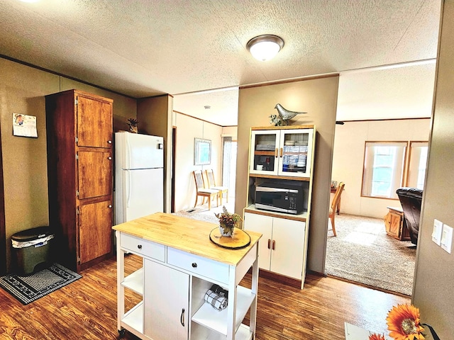 kitchen featuring a textured ceiling, white fridge, and dark hardwood / wood-style floors